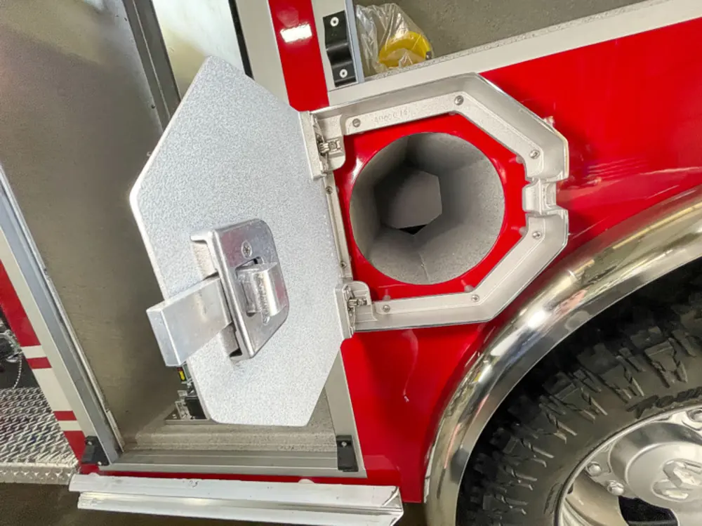 Exterior view of small fire truck showing cab, body compartments, and wheel/tire area.